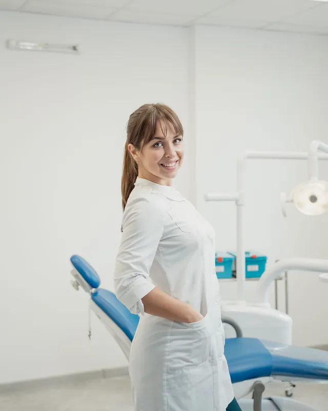 Jess Miller in a white tunic, standing next to a treatment chair