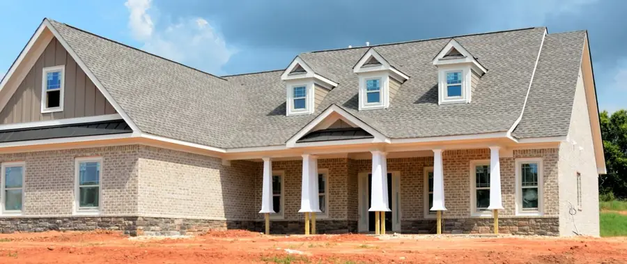 Light gray shingle roof with three dormers on a new brick ranch home