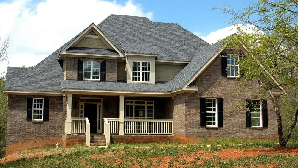 Gray architectural shingle roof on a two-story brick home with a covered porch