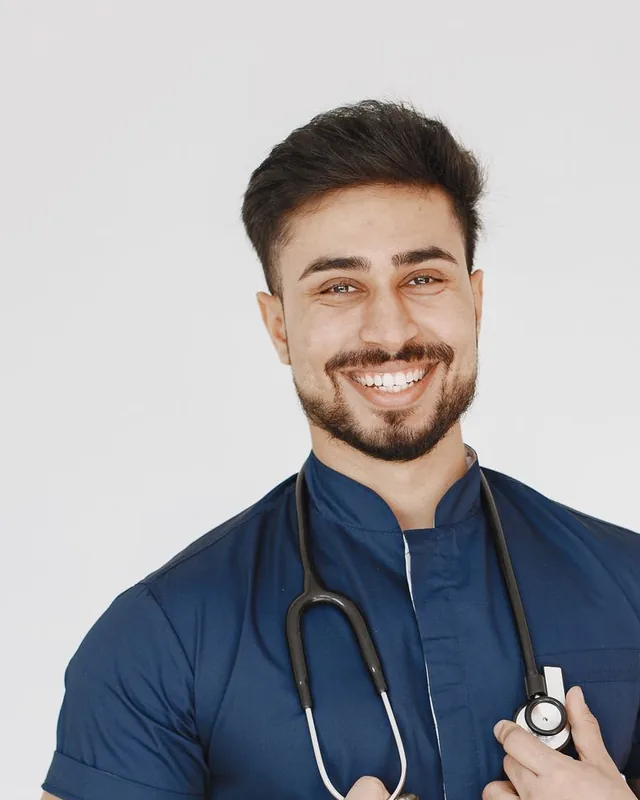 Adrian Costa, registered nurse and injector, smiling in a navy tunic with a stethoscope