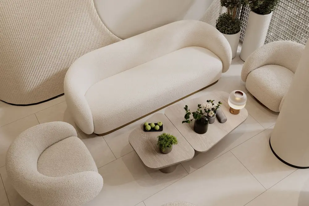 A cream curved sofa and two round armchairs around a low wooden table with small plants, in a quiet waiting area