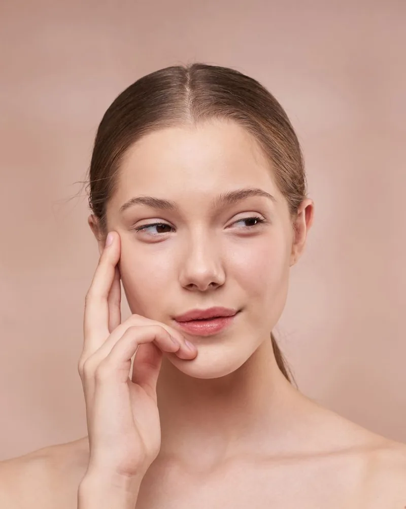 A woman with natural, unretouched skin resting her hand against her cheek