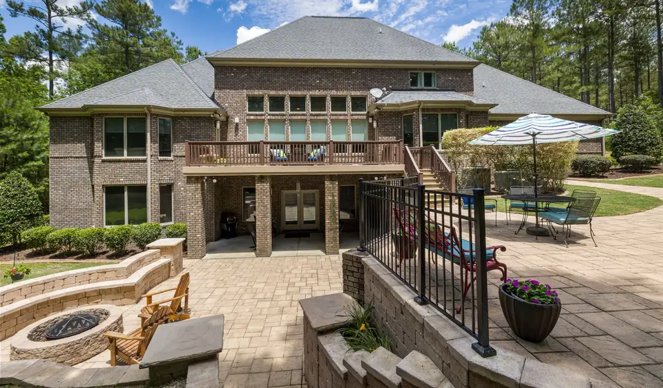 Tiered paver terrace with a curved stacked-stone seat wall and fire pit behind a brick home